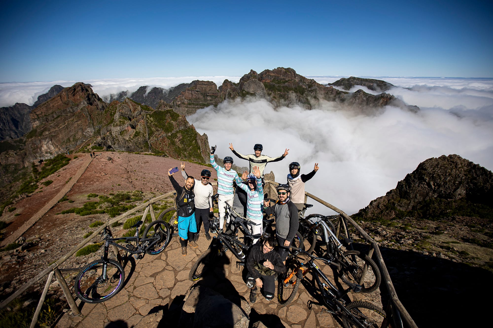 Riders celebrating on a mountain summit above a sea of clouds